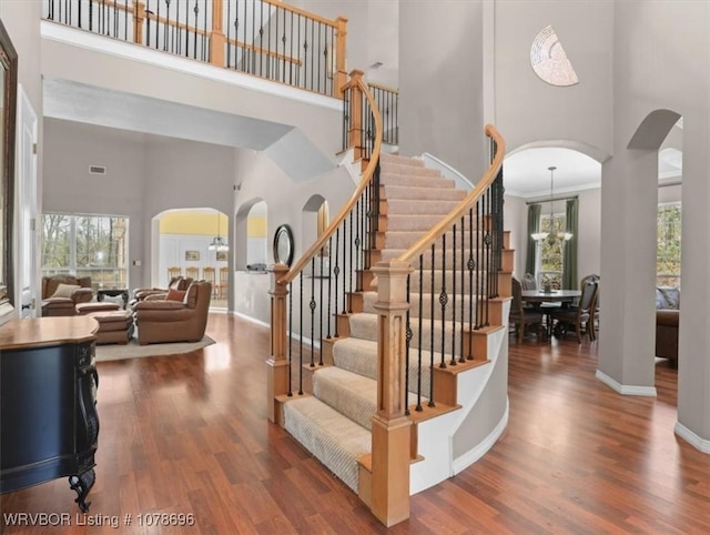 stairs with hardwood / wood-style flooring, a wealth of natural light, and an inviting chandelier