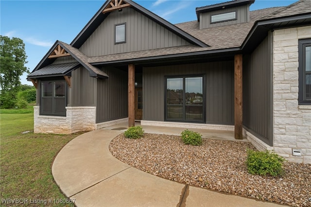 view of front of house featuring board and batten siding, a front yard, a shingled roof, and stone siding