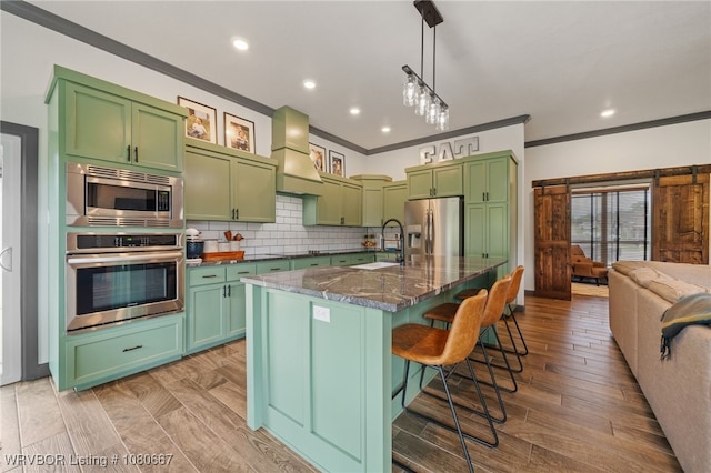 kitchen with a breakfast bar area, stainless steel appliances, a sink, and green cabinets