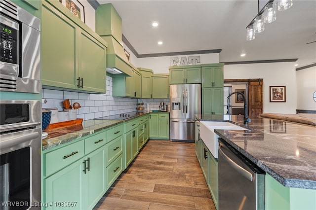 kitchen with backsplash, a sink, ornamental molding, green cabinetry, and stainless steel appliances
