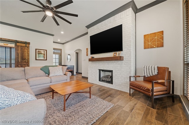 living room with arched walkways, ornamental molding, a ceiling fan, and wood finished floors