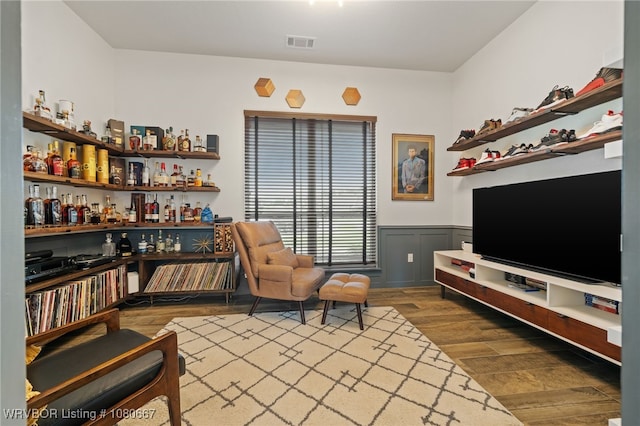 living area featuring a wainscoted wall, wood finished floors, and visible vents