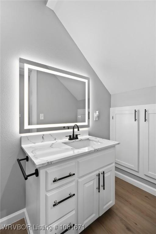 179 E Grove St, Magazine, AR 72943 - bathroom featuring vaulted ceiling, vanity, and wood finished floors