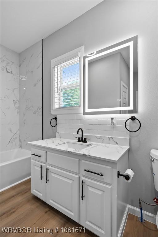 179 E Grove St, Magazine, AR 72943 - full bathroom with vanity, wood finished floors, washtub / shower combination, and backsplash