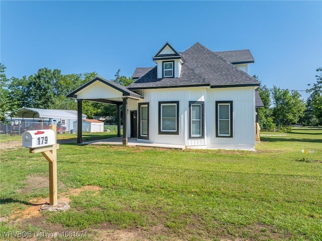 179 E Grove St, Magazine, AR 72943 - view of front facade with a detached carport, roof with shingles, and a front lawn