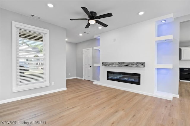 179 E Grove St, Magazine, AR 72943 - unfurnished living room with light wood-style floors, a glass covered fireplace, ceiling fan, and recessed lighting