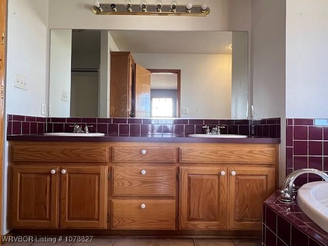 bathroom with tiled tub, vanity, tile patterned floors, and decorative backsplash