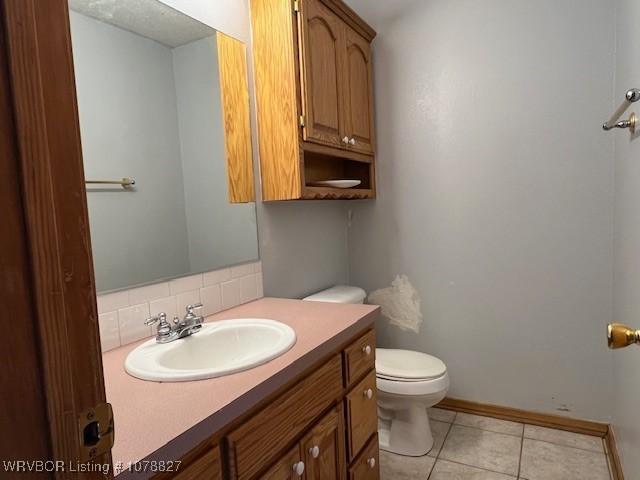 bathroom with tasteful backsplash, tile patterned floors, vanity, and toilet