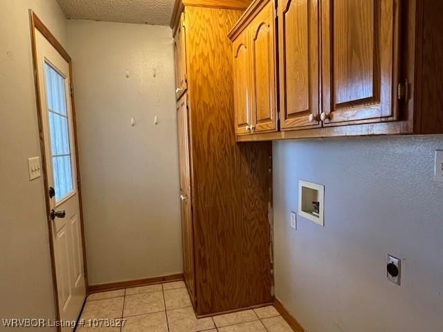 clothes washing area with light tile patterned flooring, cabinets, a textured ceiling, washer hookup, and hookup for an electric dryer