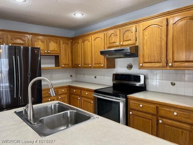 kitchen featuring black fridge, tasteful backsplash, sink, and stainless steel electric range