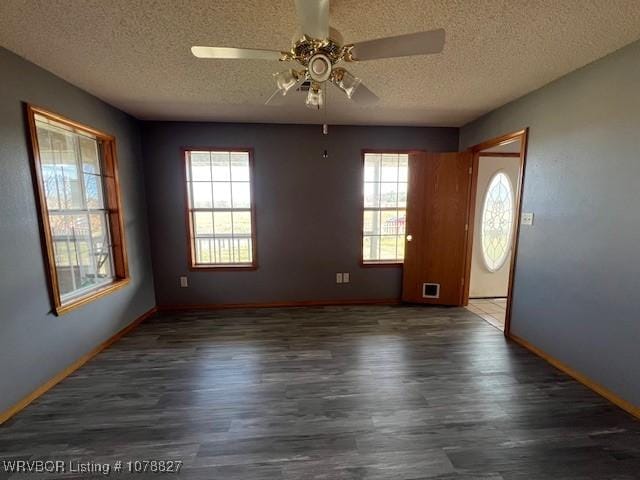 unfurnished room featuring ceiling fan, dark hardwood / wood-style floors, a textured ceiling, and a wealth of natural light