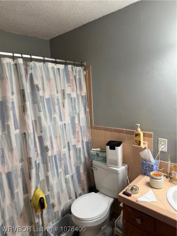 bathroom with curtained shower, tile walls, a textured ceiling, and toilet