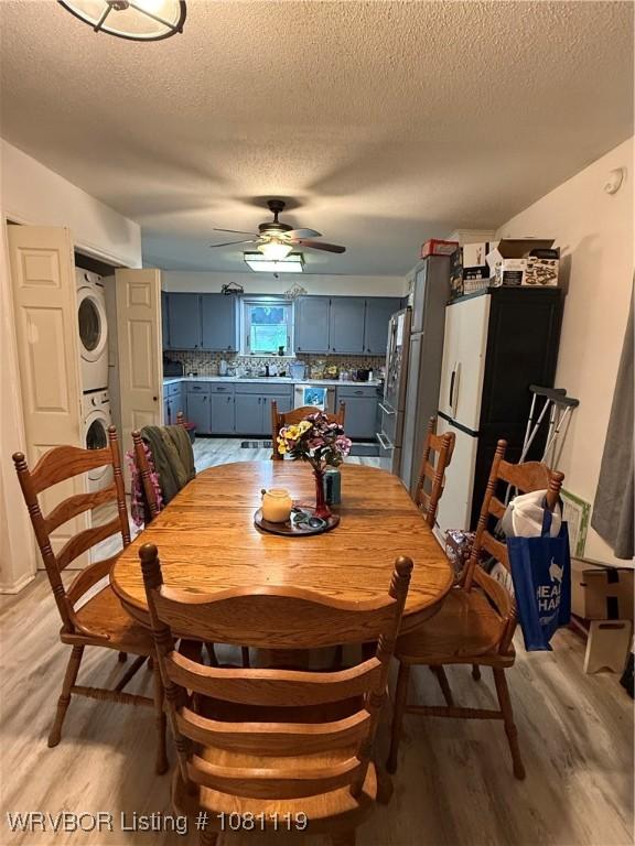 2303 Willow St, Van Buren, AR 72956 - dining space with stacked washing machine and dryer, light wood finished floors, ceiling fan, and a textured ceiling
