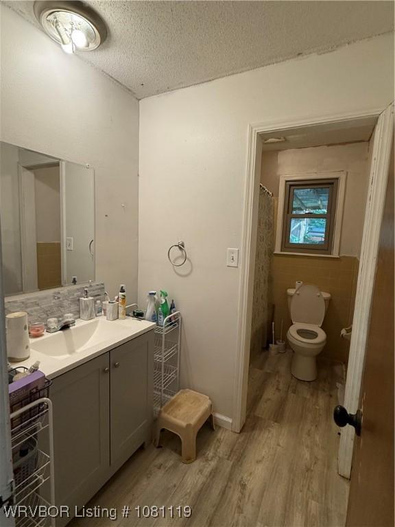2303 Willow St, Van Buren, AR 72956 - full bath with wood finished floors, toilet, vanity, a textured ceiling, and tasteful backsplash