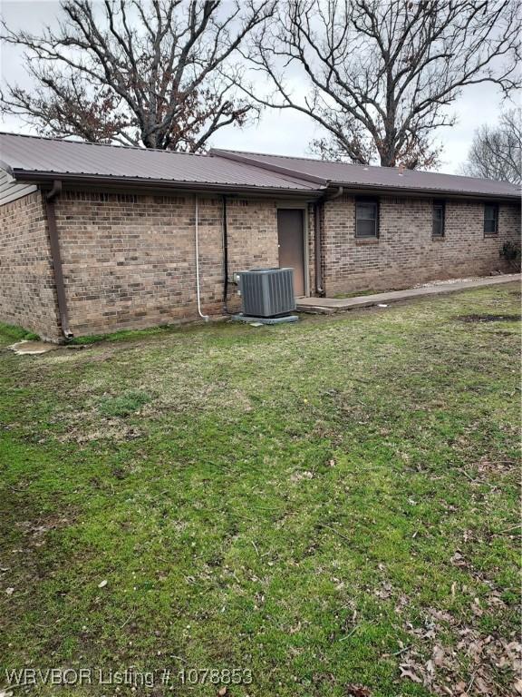 rear view of property with cooling unit and a lawn