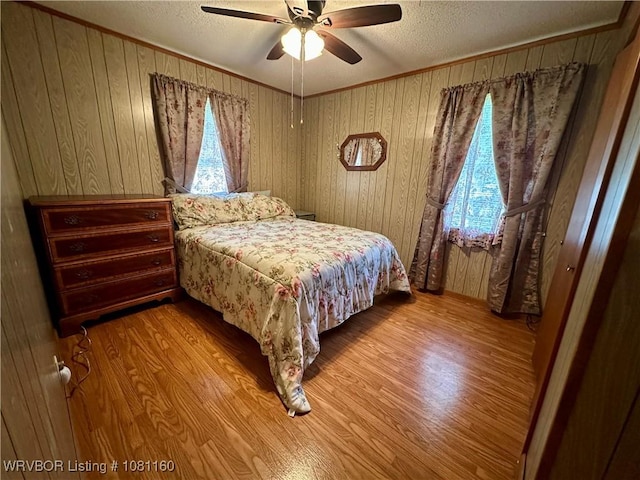 105 7th St, Paris, AR 72855 - bedroom with a textured ceiling, wood finished floors, wooden walls, ceiling fan, and ornamental molding