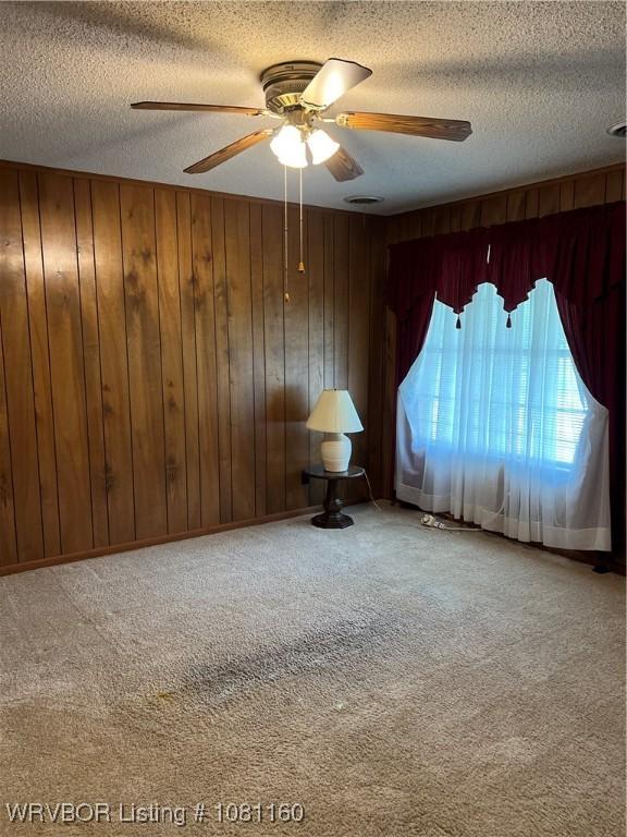 105 7th St, Paris, AR 72855 - spare room with a textured ceiling, ceiling fan, carpet, and wooden walls