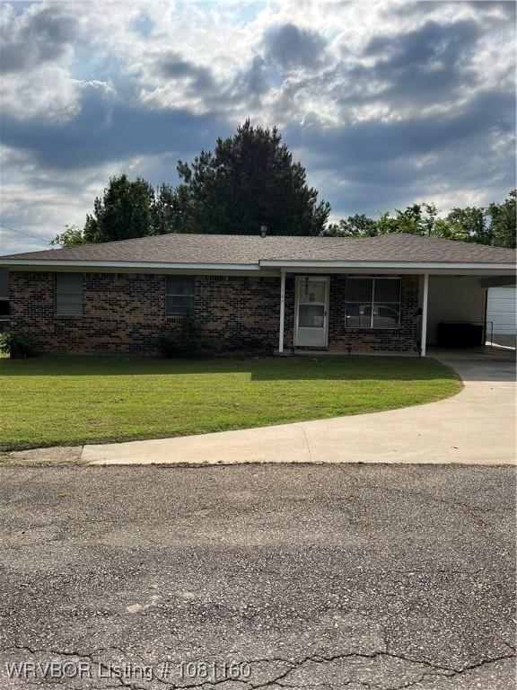 105 7th St, Paris, AR 72855 - ranch-style home featuring a front lawn, driveway, a carport, and brick siding