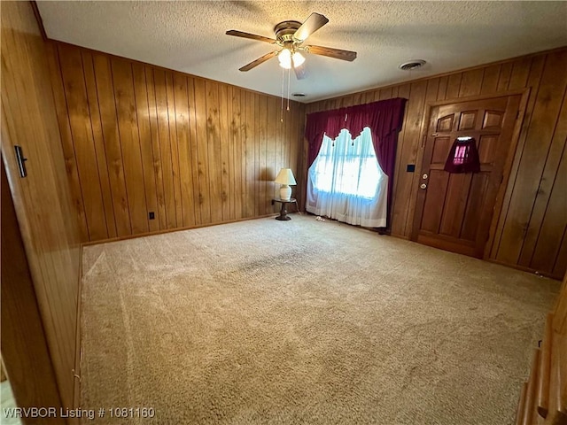 105 7th St, Paris, AR 72855 - carpeted empty room with a textured ceiling, wood walls, and a ceiling fan
