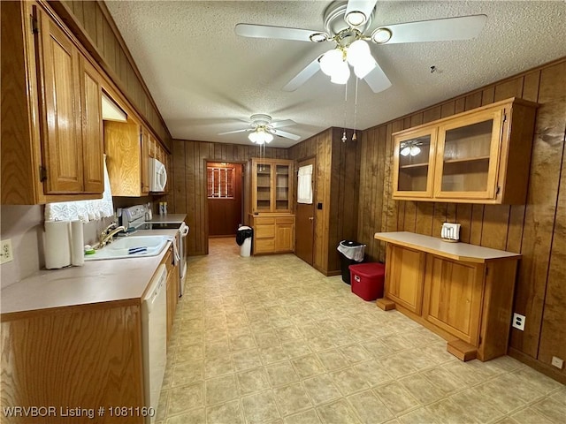105 7th St, Paris, AR 72855 - kitchen featuring white appliances, a textured ceiling, wood walls, a ceiling fan, and brown cabinetry