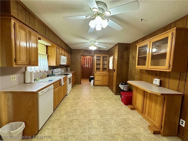 105 7th St, Paris, AR 72855 - kitchen with white appliances, a textured ceiling, wood walls, light countertops, and brown cabinets