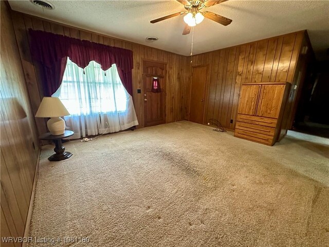 105 7th St, Paris, AR 72855 - unfurnished living room with a textured ceiling, wooden walls, carpet flooring, and ceiling fan