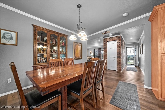 dining space with an inviting chandelier, ornamental molding, and dark wood finished floors