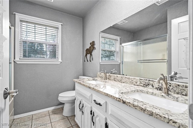 bathroom featuring toilet, a sink, tile patterned floors, and a shower stall