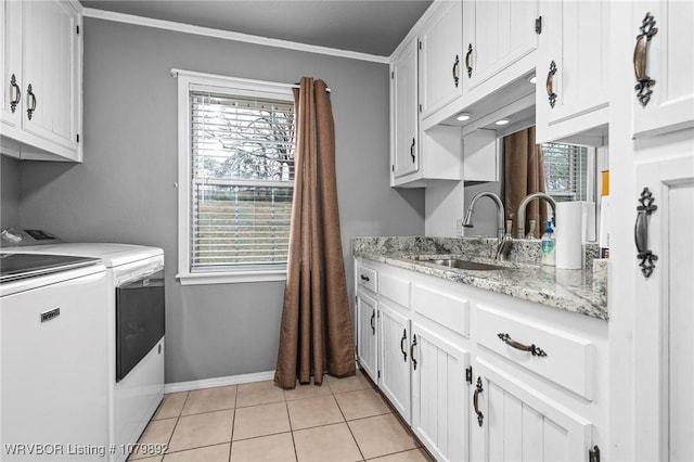 laundry area with a healthy amount of sunlight, independent washer and dryer, a sink, light tile patterned flooring, and cabinet space