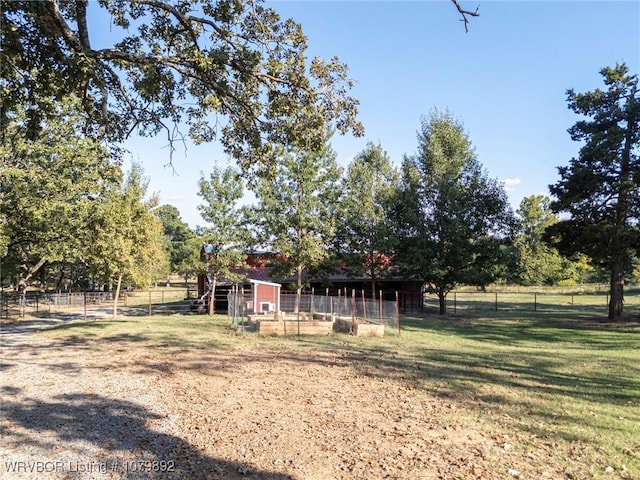 view of yard with an outbuilding, fence, a rural view, and a vegetable garden
