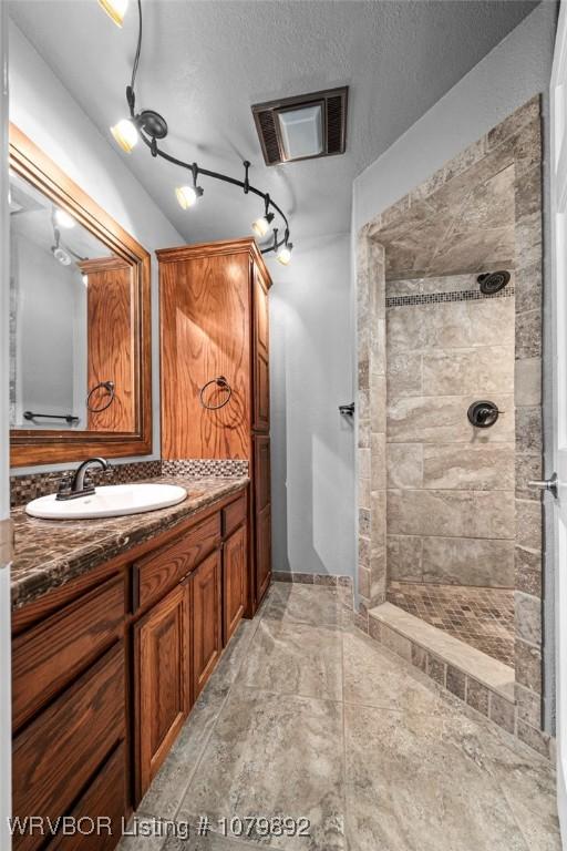 bathroom featuring visible vents, a walk in shower, vanity, and a textured ceiling
