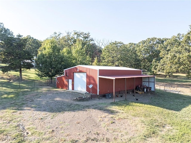 view of pole building featuring dirt driveway, fence, and a yard