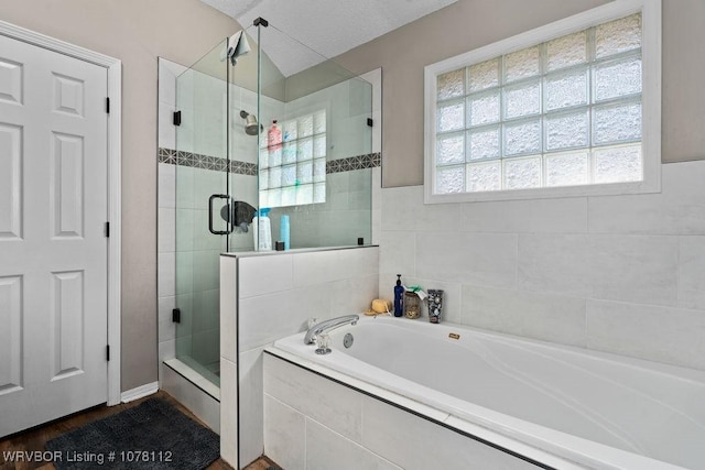 bathroom with a textured ceiling, separate shower and tub, and vaulted ceiling