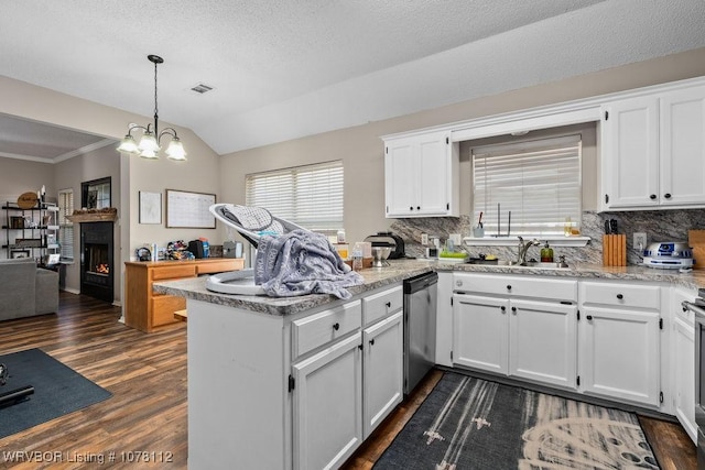 kitchen featuring stainless steel dishwasher, white cabinets, lofted ceiling, and kitchen peninsula