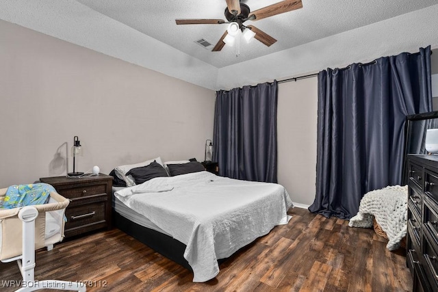 bedroom with a textured ceiling, ceiling fan, and dark wood-type flooring