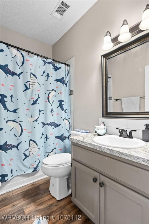 bathroom featuring tasteful backsplash, vanity, a textured ceiling, hardwood / wood-style flooring, and toilet