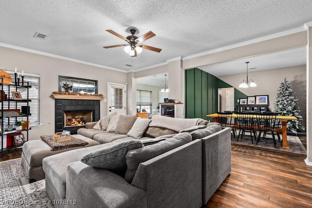 living room with ceiling fan with notable chandelier, a healthy amount of sunlight, crown molding, and a textured ceiling