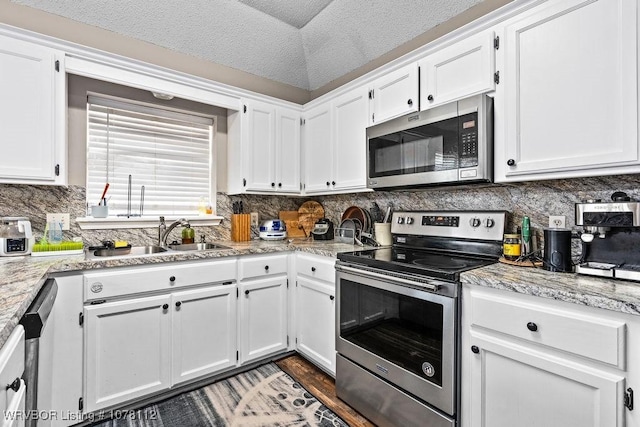 kitchen with light stone countertops, sink, stainless steel appliances, a textured ceiling, and white cabinets