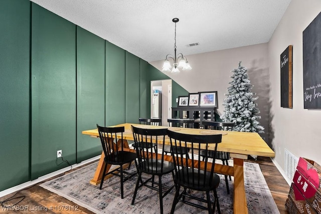 dining area with a chandelier, a textured ceiling, and dark hardwood / wood-style flooring