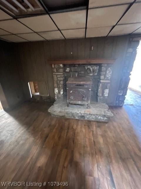 room details featuring a paneled ceiling, a wood stove, and wood finished floors