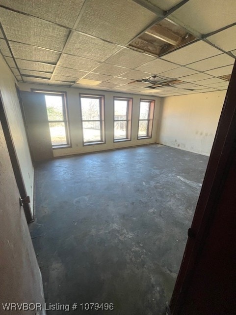 unfurnished room featuring a paneled ceiling and concrete floors