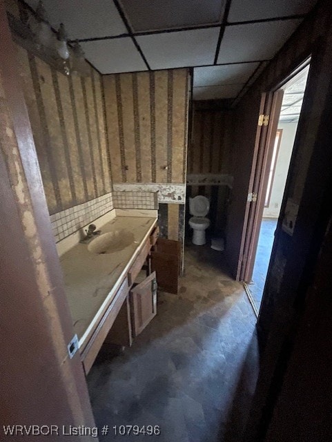 bathroom featuring backsplash, a drop ceiling, toilet, and vanity