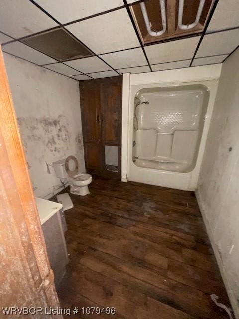 full bathroom featuring a bath, a drop ceiling, toilet, and wood finished floors