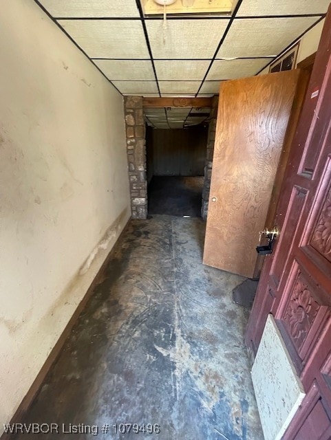 hall featuring a paneled ceiling and concrete floors