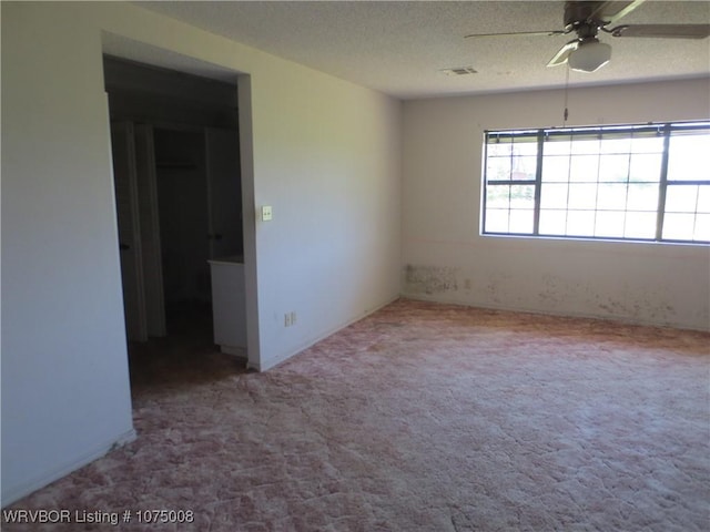 empty room with carpet, ceiling fan, and a textured ceiling