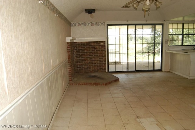 unfurnished living room featuring light tile patterned floors, a textured ceiling, ceiling fan, and lofted ceiling