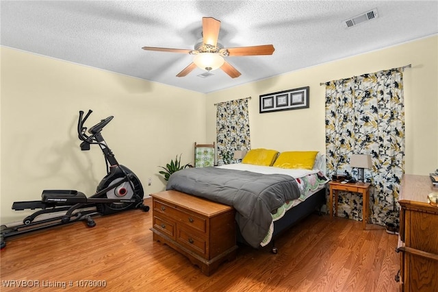 bedroom with ceiling fan, a textured ceiling, and light wood-type flooring