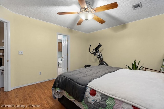 bedroom featuring ceiling fan, light hardwood / wood-style floors, a textured ceiling, and ensuite bath