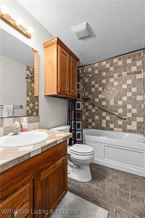 full bathroom featuring vanity, a textured ceiling, toilet, and tiled shower / bath combo