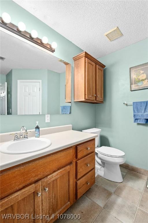 bathroom featuring vanity, toilet, and a textured ceiling